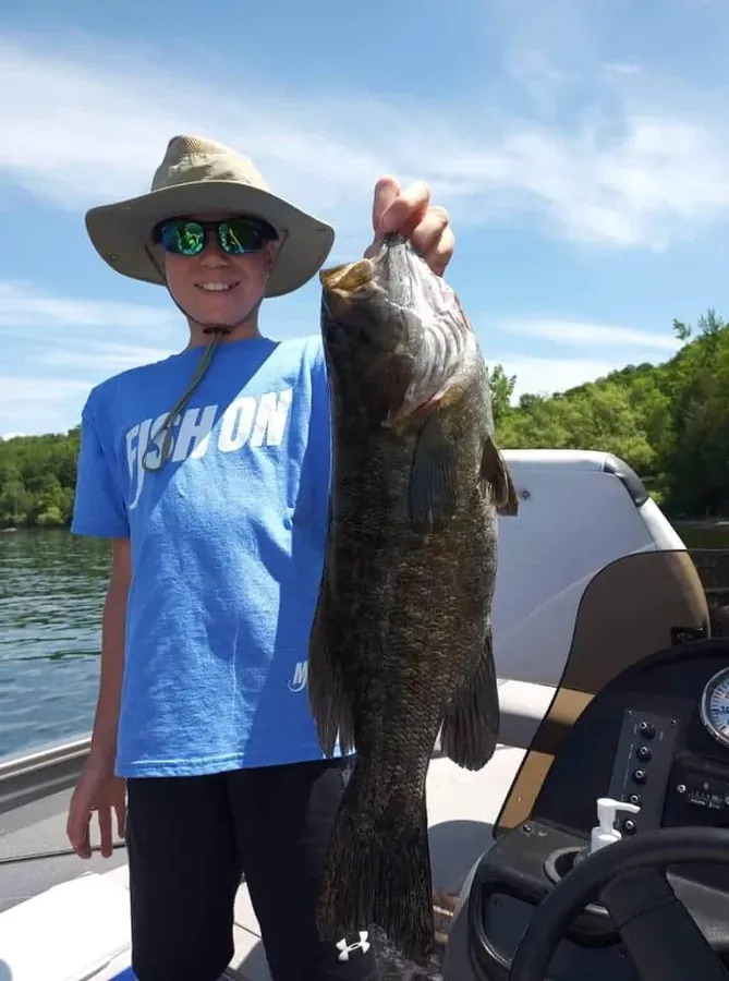 Enfant souriant avec sa prise lors d'une sortie de pêche guidée en famille en Estrie